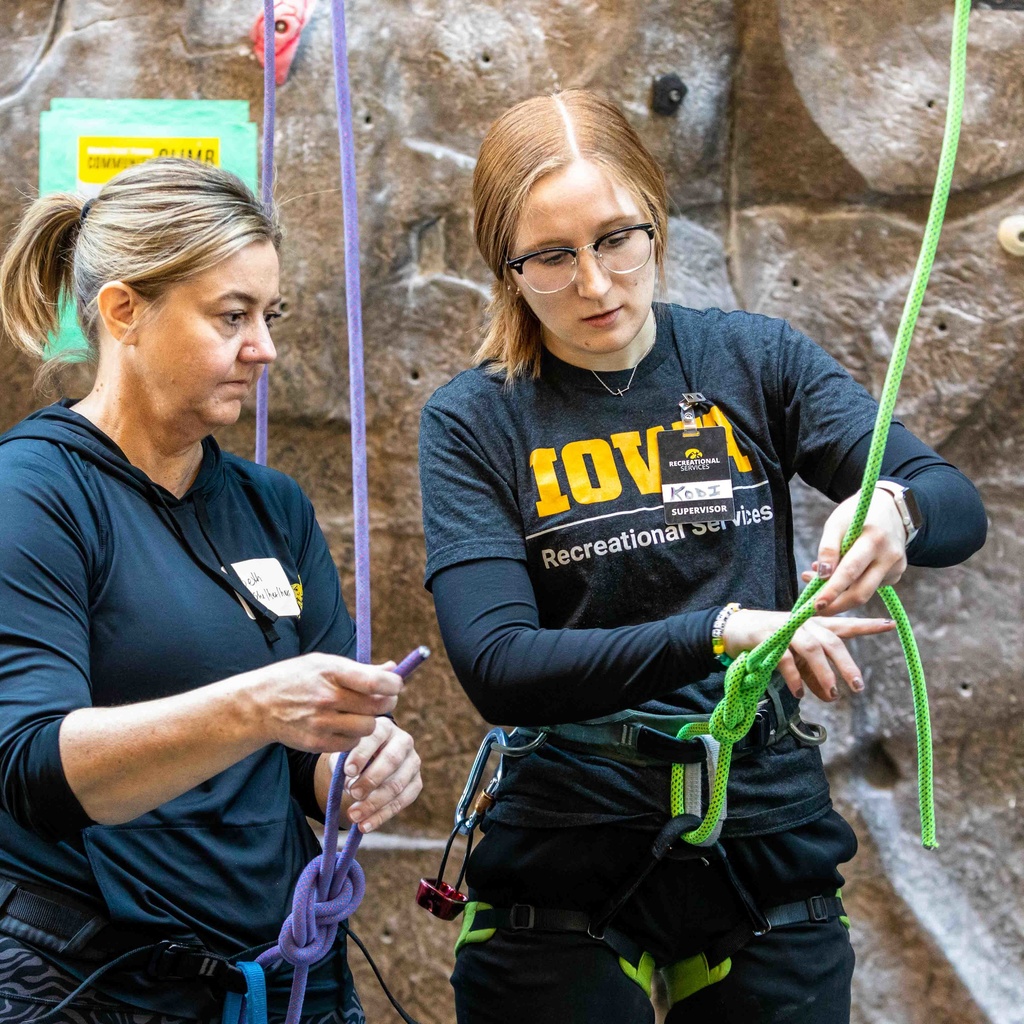 Staff member teaches climber how to tie a specific knot