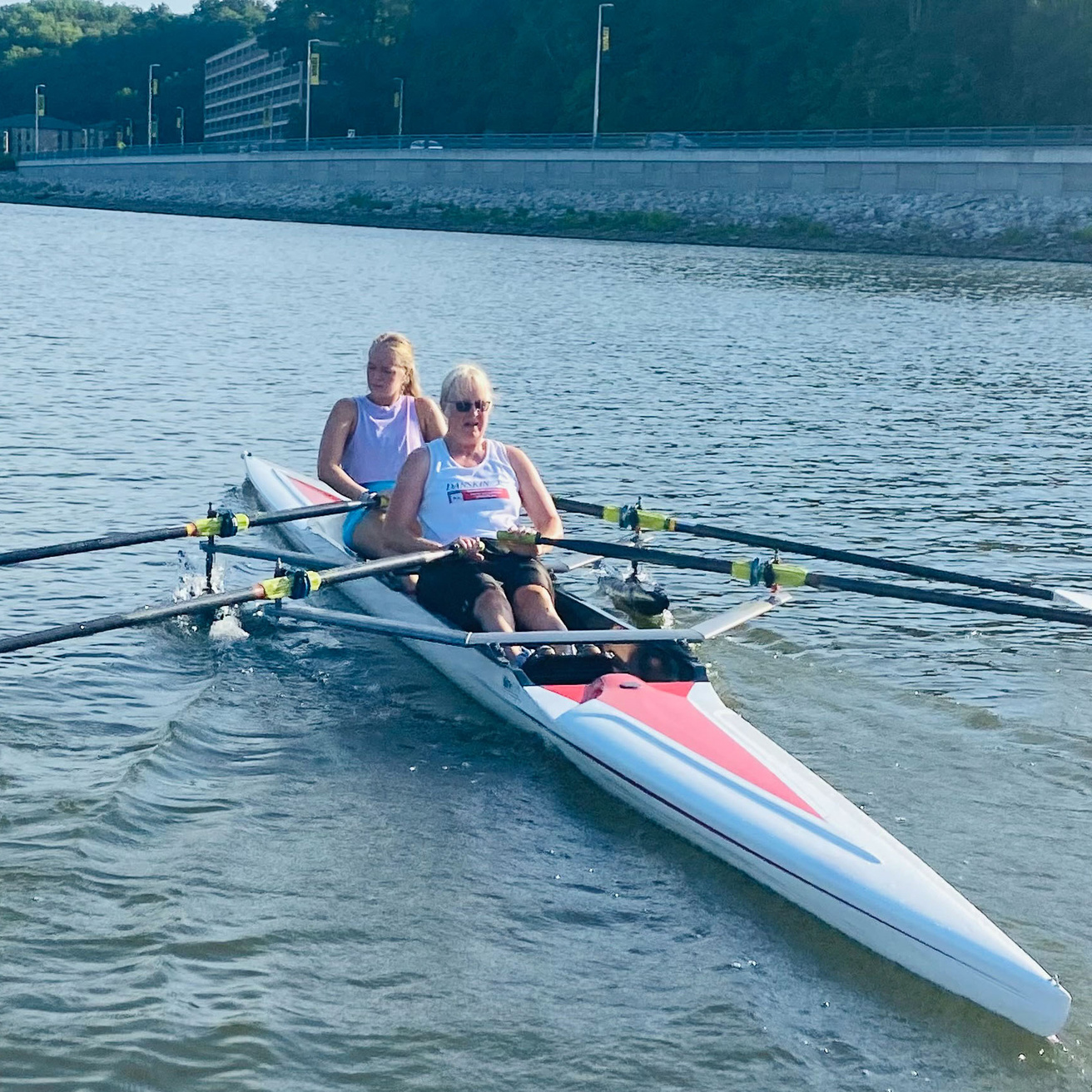 Two rowers in a boat on the Iowa River participating in a private rowing lesson.