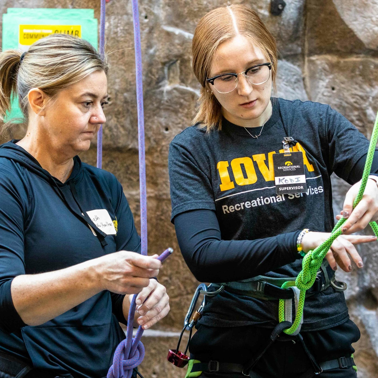 A staff member demonstrating how to tie a specific knot while standing next to a participant.